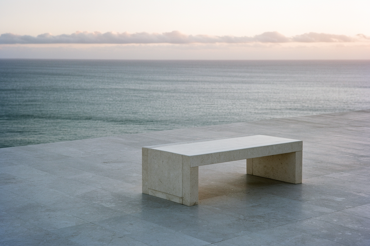 Stone bench on an empty terrace overlooking open water at dawn