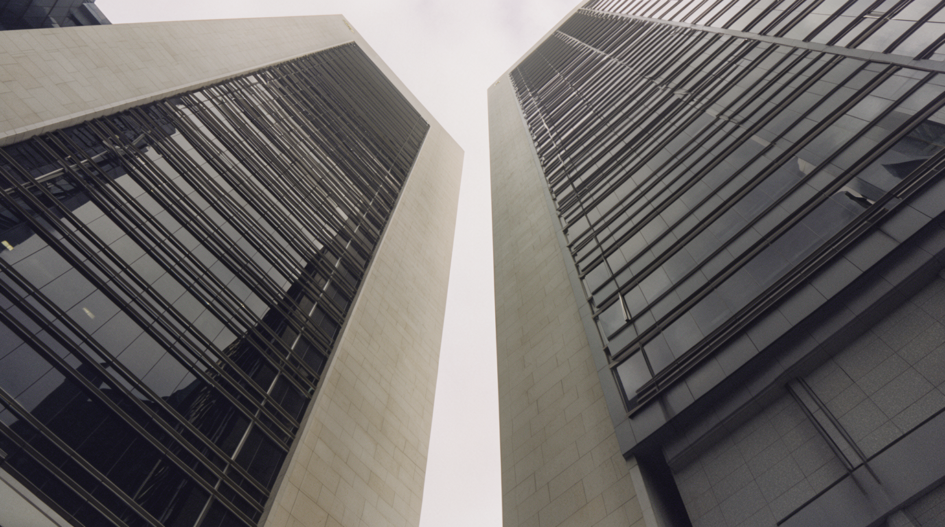Two towers converging above a narrow wedge of sky in Raffles Place