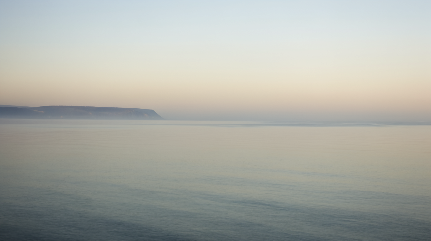 Calm open sea meeting a pale gradient sky at dawn